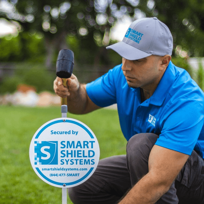 Smart Shield Systems technician installing security sign