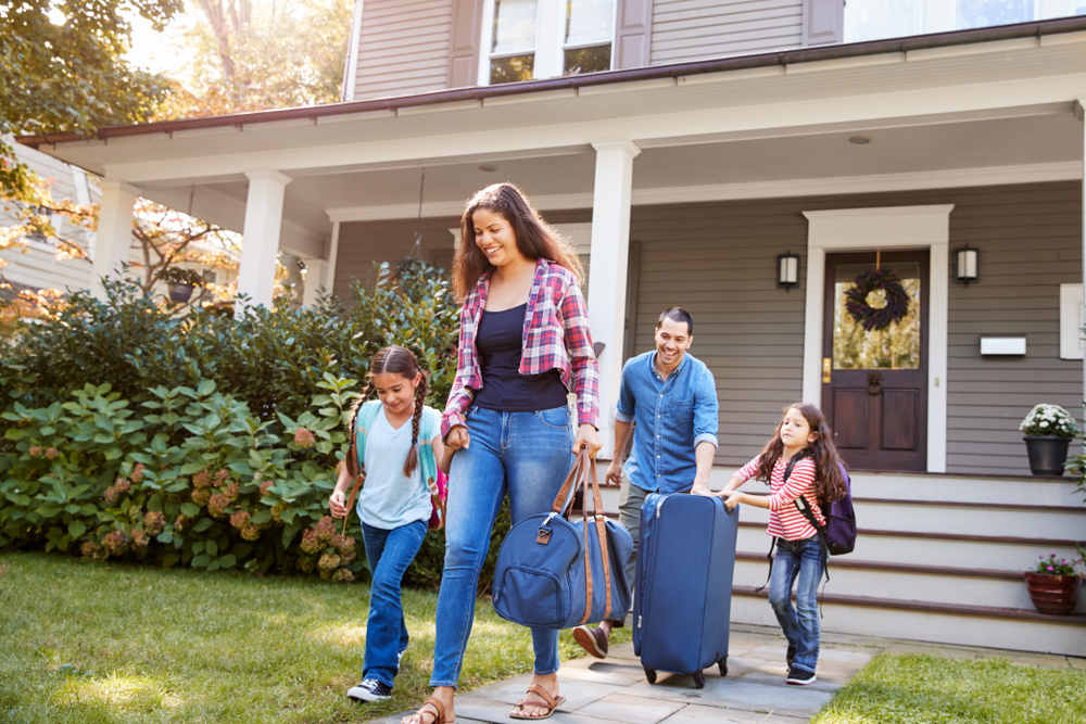 Family With Luggage Leaving House For Vacation - 4 Ways to Protect Your Home While on Vacation