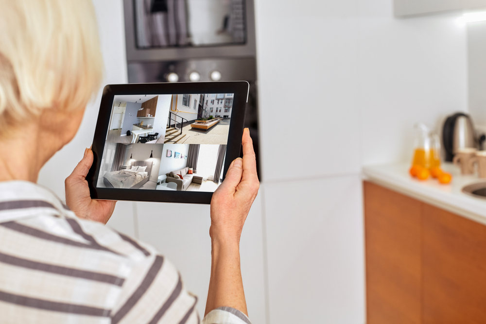 Senior woman looking at camera surveillance via tablet - Benefits of Home Security for Seniors